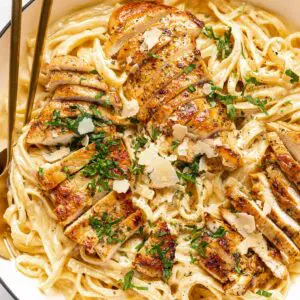 Grilled chicken served over creamy fettuccine pasta with herbs.