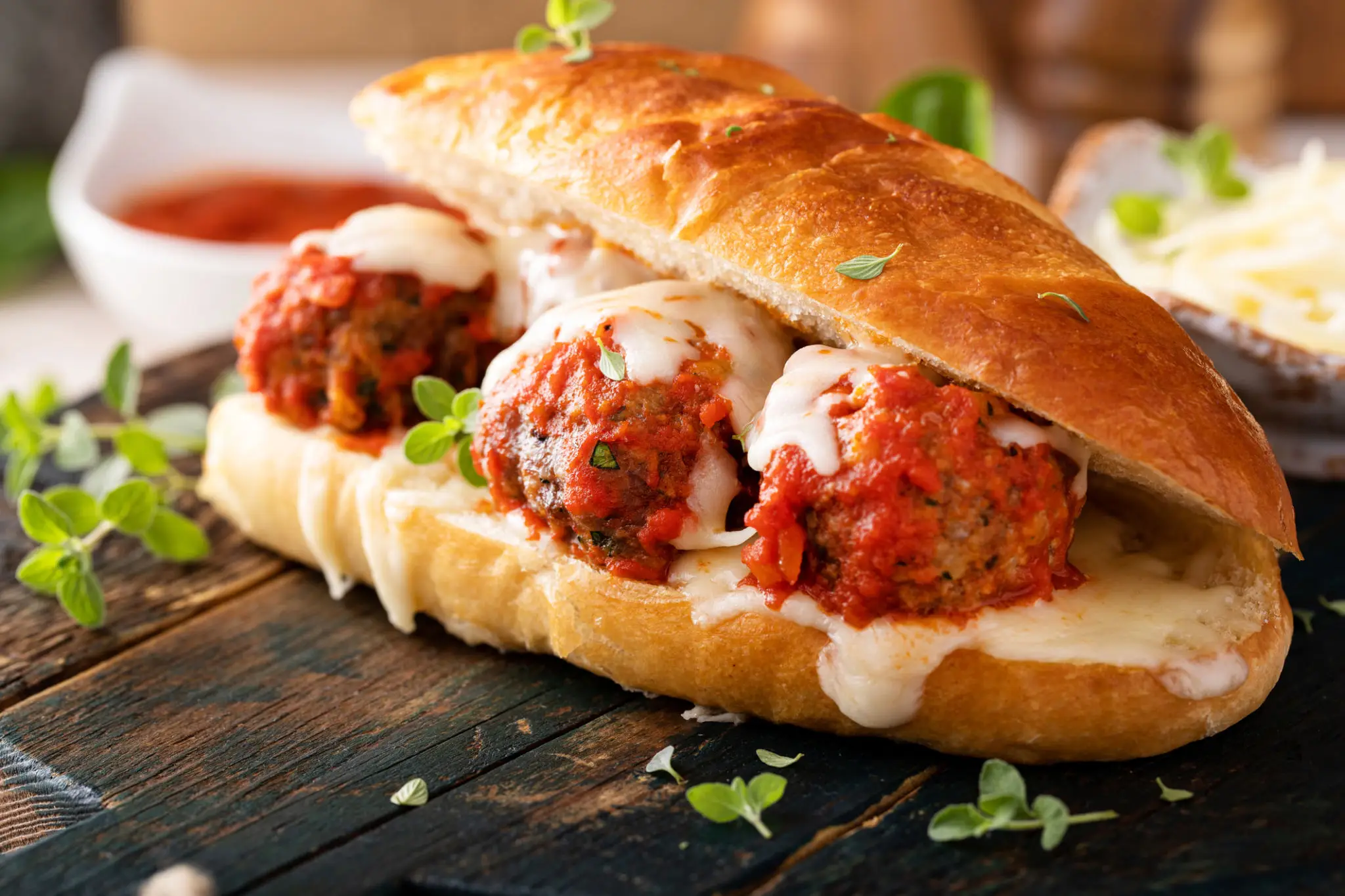 Meatball sandwich with marinara and melted cheese in a crusty roll.
