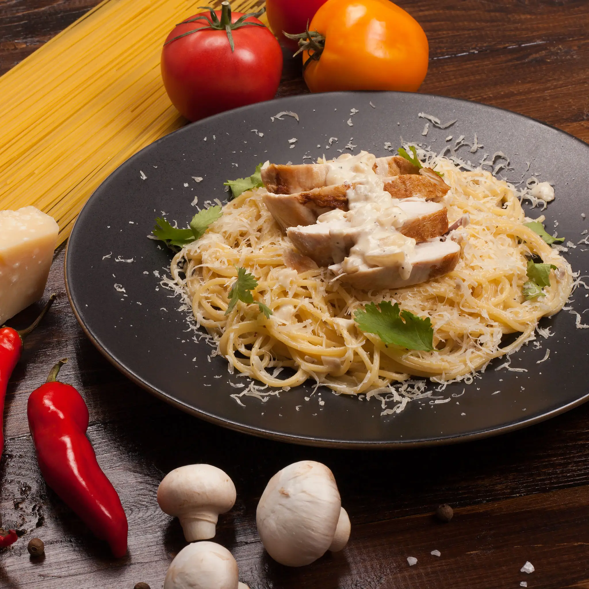 A plate of pasta with chicken and herbs on a wooden table.