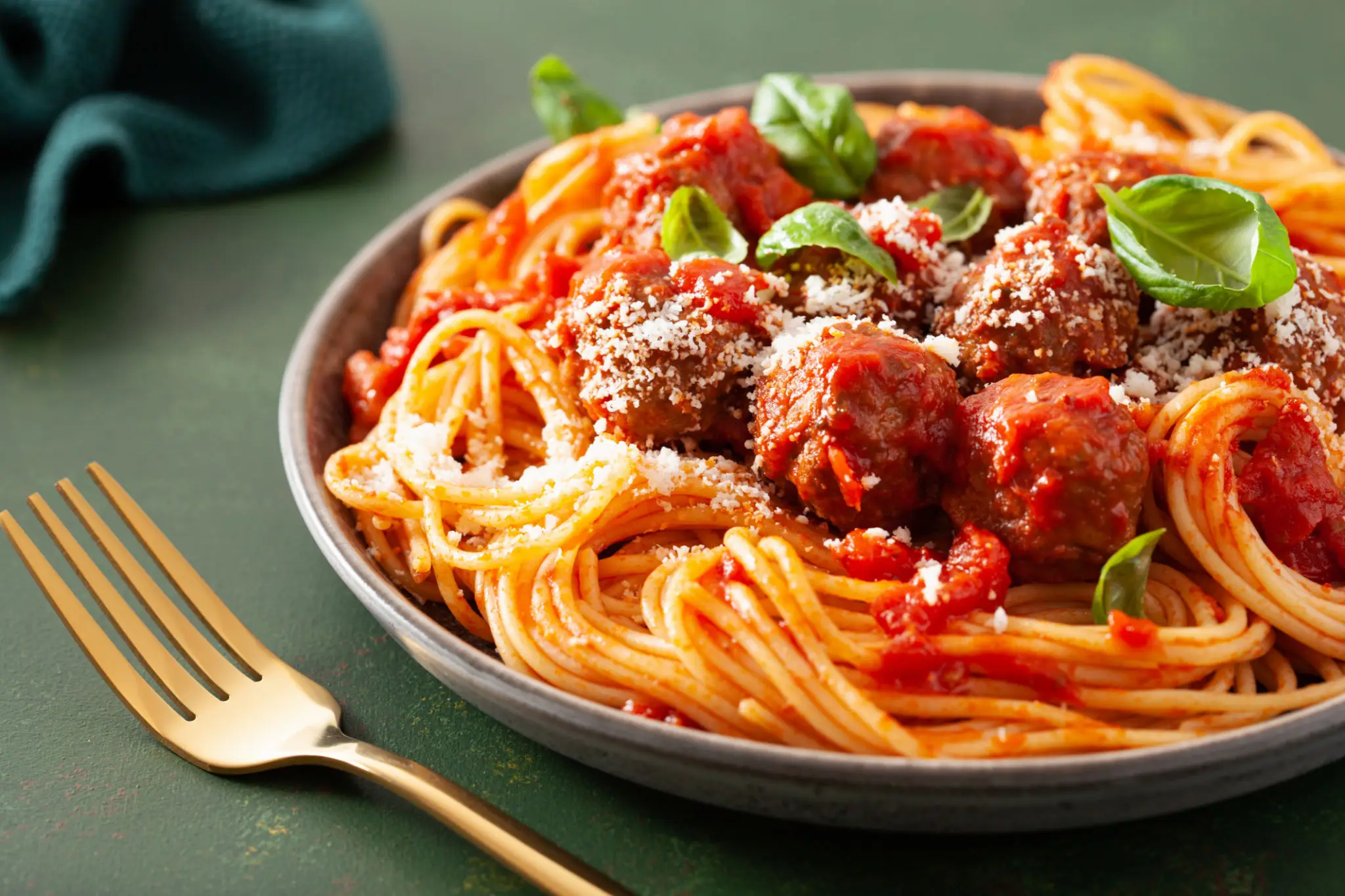 Plate of spaghetti with meatballs and tomato sauce, garnished with basil.